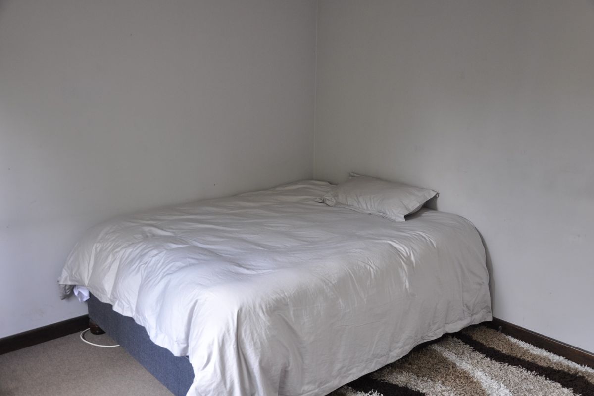 A simple bedroom featuring neutral wall finishes and carpeted flooring, providing a blank canvas for personalization.