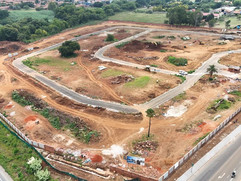 Aerial view of a residential development site showing internal road infrastructure, perimeter fencing, and cleared land ready for construction.