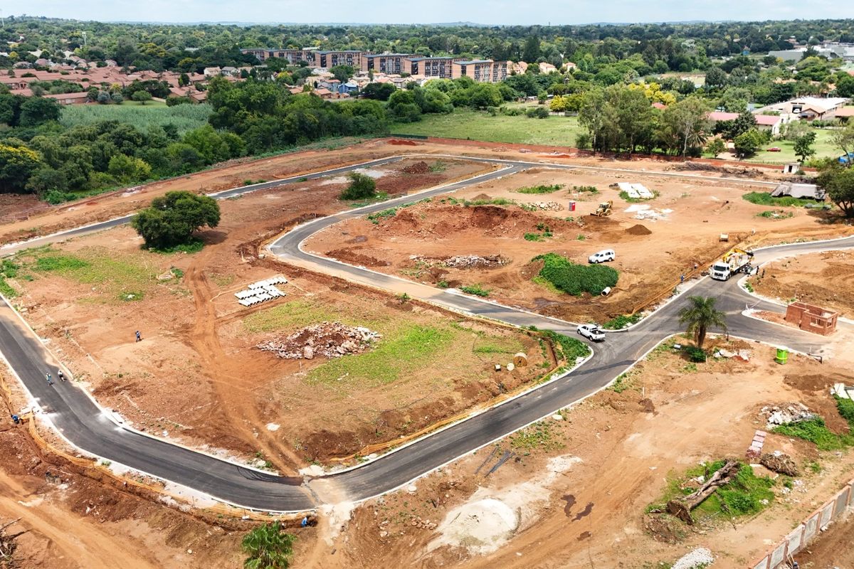 Aerial view of a residential development site featuring newly paved internal roads and cleared plots ready for construction.