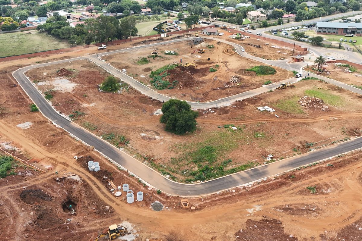 Aerial view of a residential development site showing cleared land, newly paved roads, and ongoing infrastructure installation.