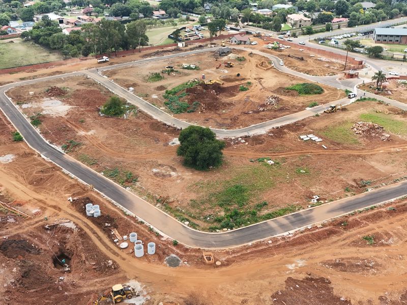 Aerial view of a residential development site showing cleared land, newly paved roads, and ongoing infrastructure installation.