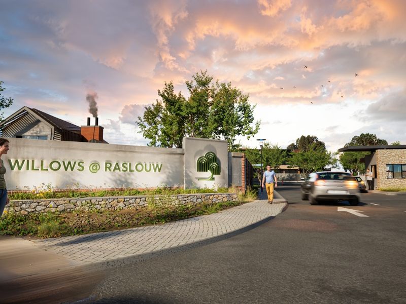 The entrance to Willows @ Raslouw residential estate, featuring a stone-accented boundary wall, security gatehouse, and well-maintained paved access road.