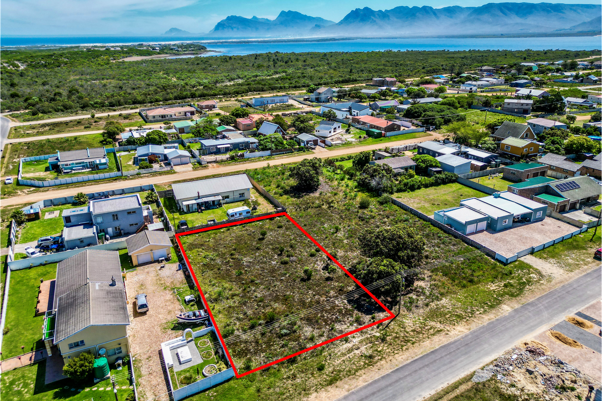 An aerial view of a vacant residential plot in a coastal neighborhood, highlighting the property boundaries and surrounding landscape.