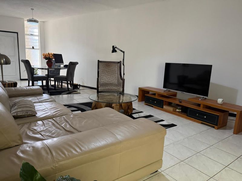 Spacious open-plan living and dining area featuring neutral ceramic floor tiles and natural light from a large window.