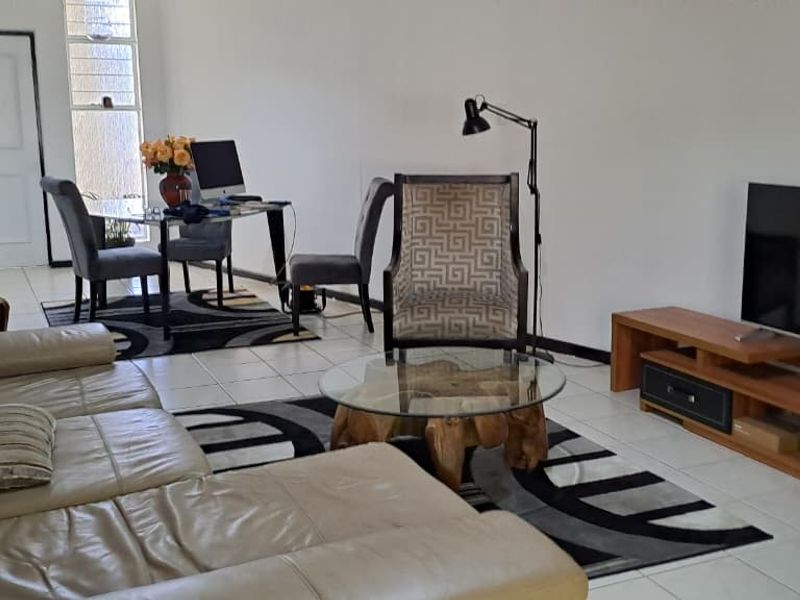 A spacious living area featuring neutral tiled flooring and a large window, providing a bright and functional space for relaxation and dining.