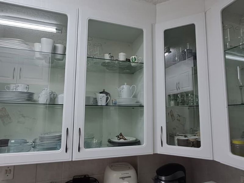 A kitchen area featuring white glass-fronted cabinetry, a built-in wine rack, and a tiled backsplash.