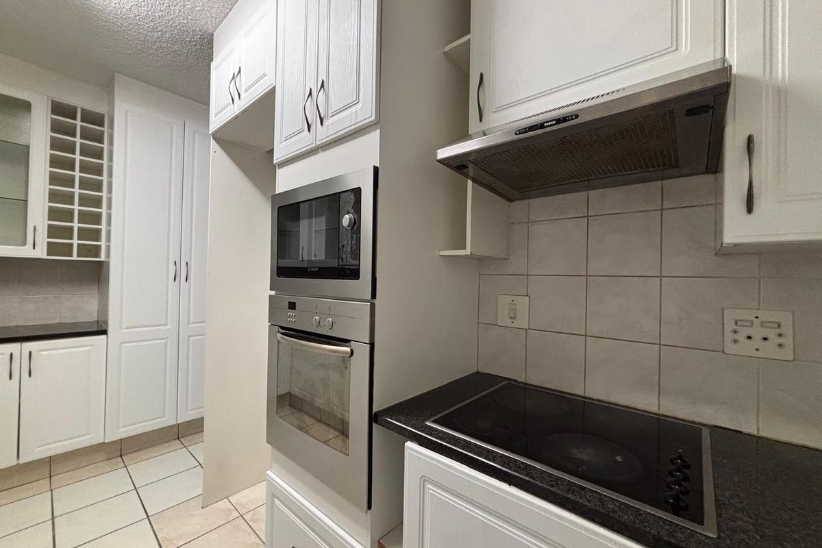 A functional kitchen featuring built-in appliances, granite countertops, tiled backsplash, and ample white cabinetry, offering a clean and practical workspace.