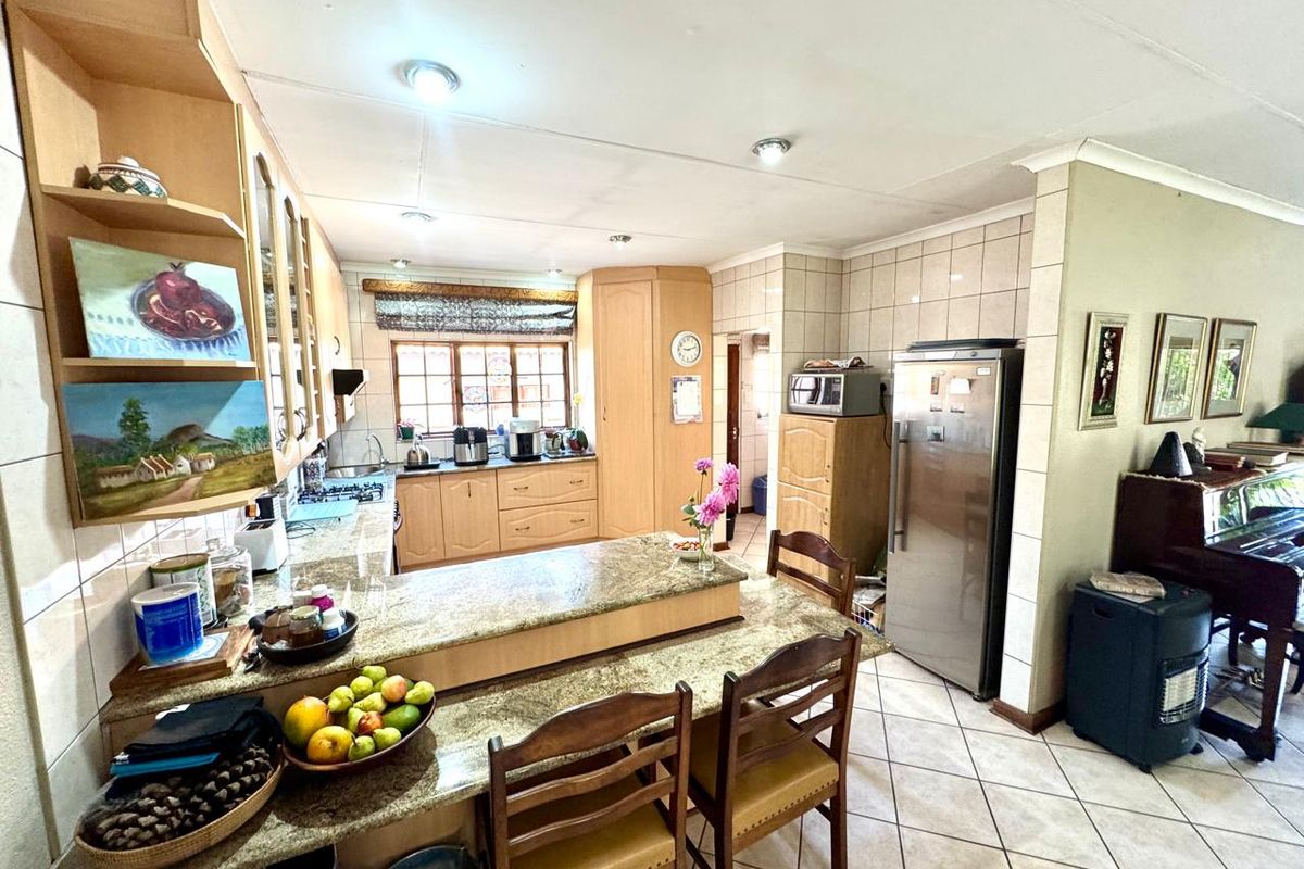 A functional kitchen featuring granite countertops, a breakfast bar, built-in cabinetry, and tiled flooring, offering a practical layout for daily meal preparation.