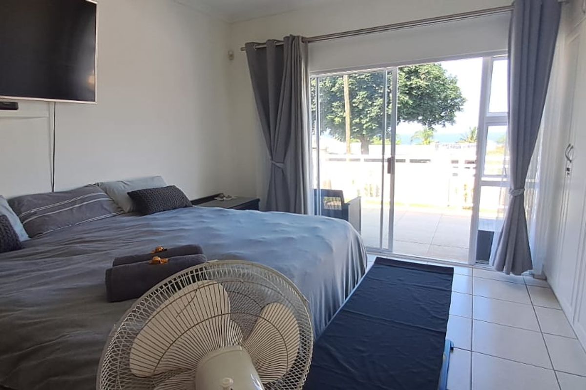 Spacious bedroom featuring built-in cupboards, tiled flooring, and a sliding glass door providing direct access to an outdoor patio area.