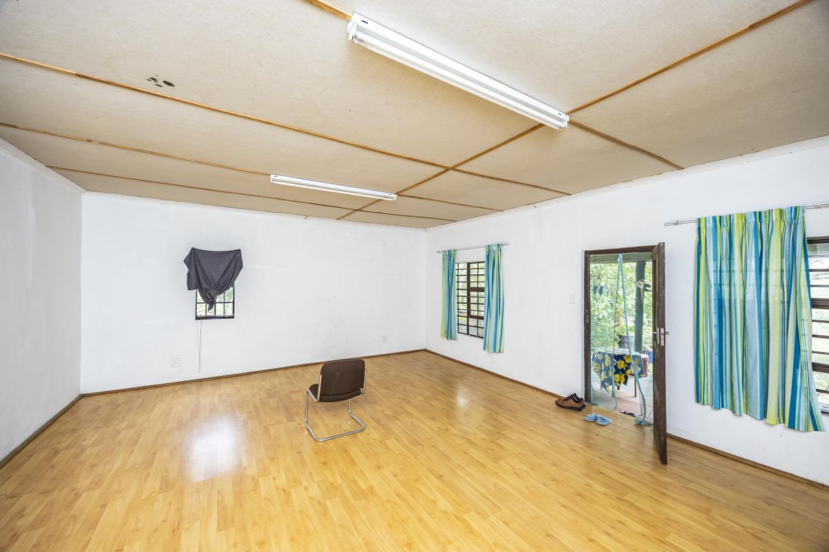 Spacious living area featuring laminate flooring, fluorescent lighting, and direct access to an outdoor patio area.