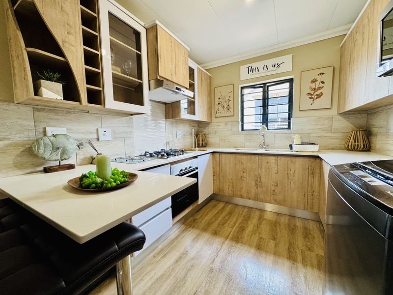 Modern kitchen featuring wood-look cabinetry, stone countertops, built-in gas hob, oven, and extractor fan with tiled backsplash and wood-style flooring.