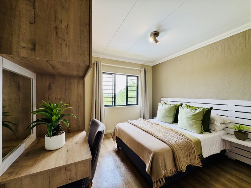 A well-maintained bedroom featuring built-in wooden cabinetry, a desk area, and a window with security bars, offering a functional and comfortable living space.