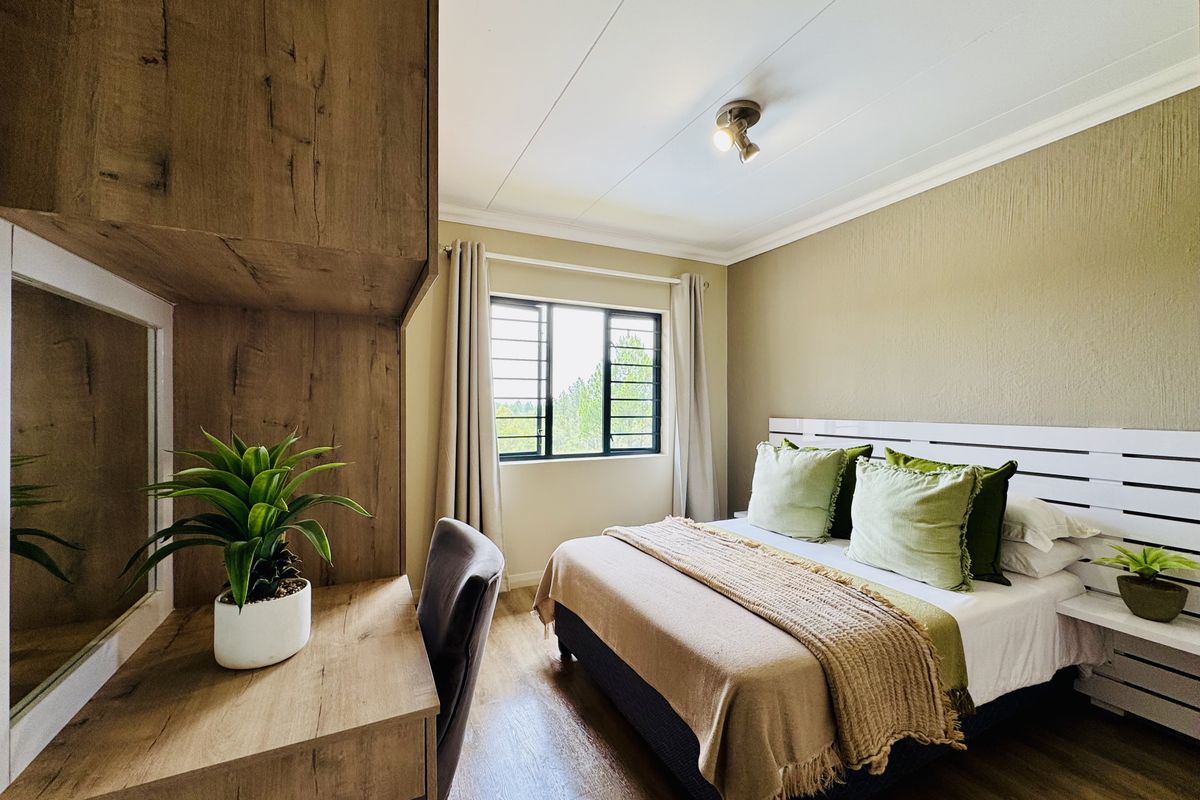 A well-maintained bedroom featuring built-in wooden cabinetry, a desk area, and a window with security bars, offering a functional and comfortable living space.