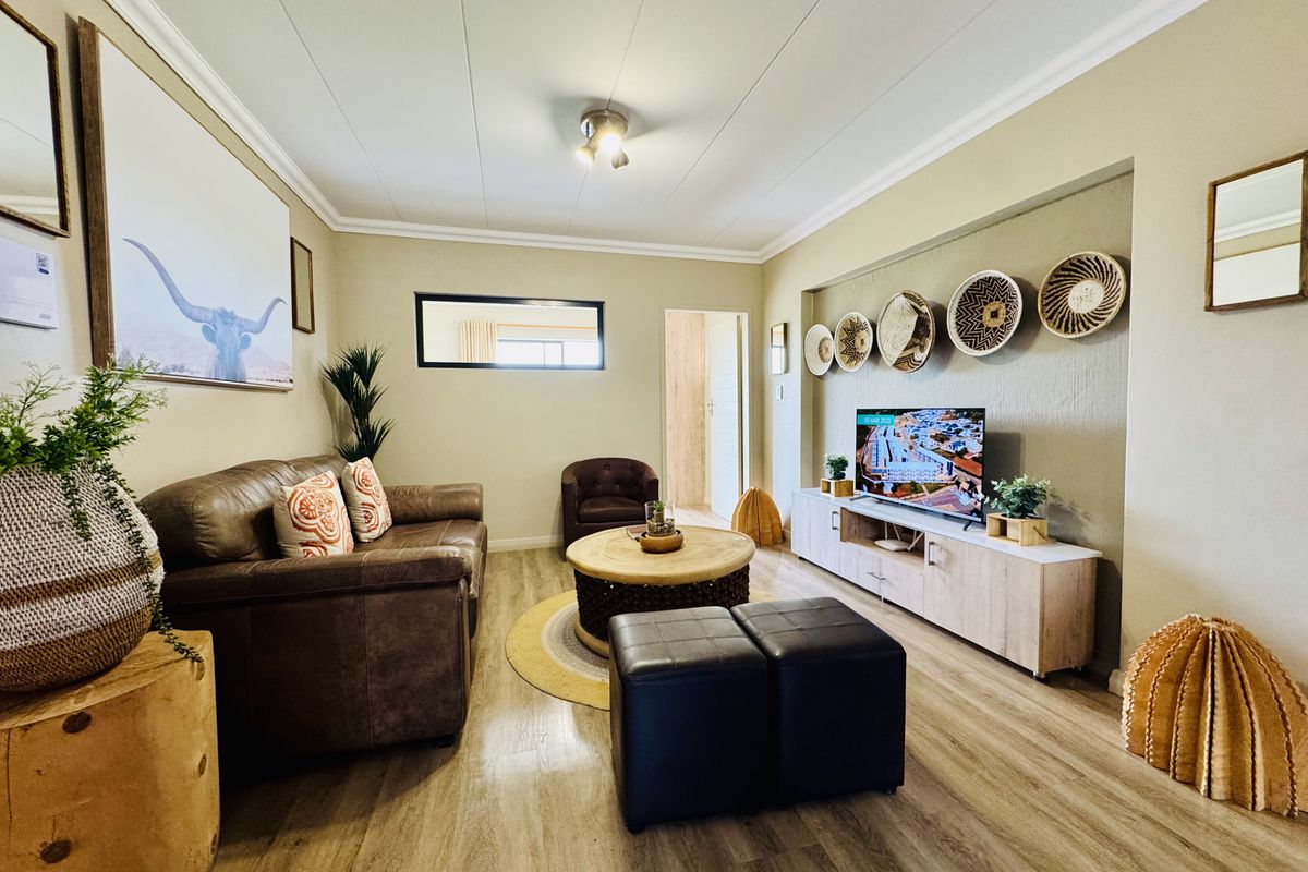 A well-maintained living room featuring wood-look flooring, crown molding, and a recessed wall niche for media storage.