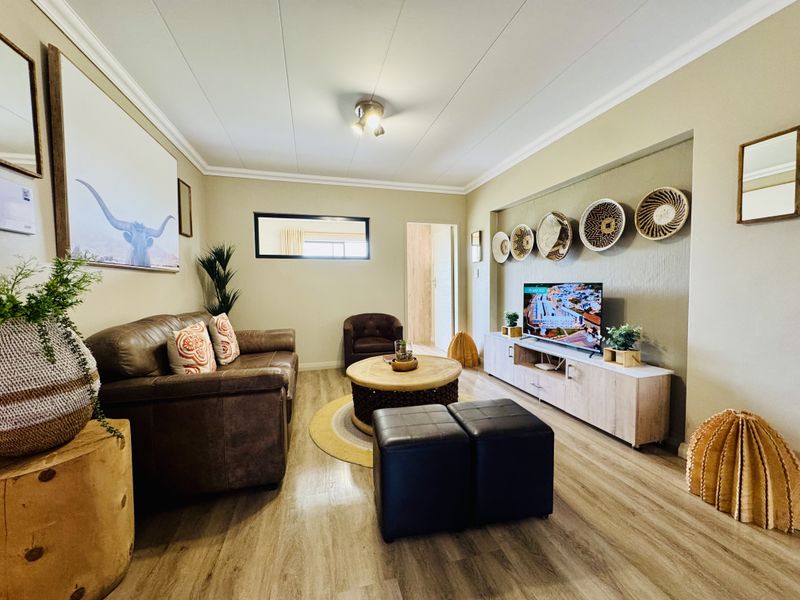 A well-maintained living room featuring wood-look flooring, crown molding, and a recessed wall niche for media storage.