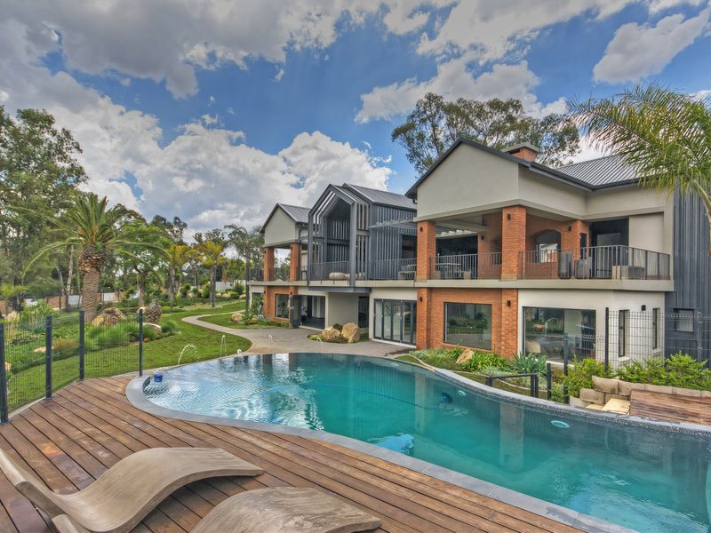 A beautifully landscaped rear exterior featuring a modern swimming pool, timber decking, and a multi-level townhouse facade with covered patio areas.