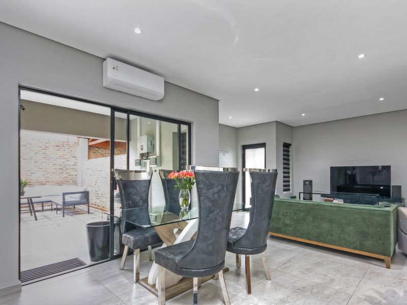 Spacious open-plan living and dining area featuring modern tiled flooring, recessed lighting, and seamless access to the outdoor patio through sliding glass doors.