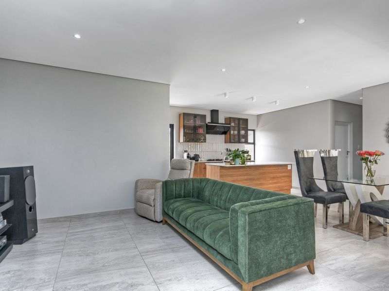Modern open-plan living and dining area featuring tiled flooring, recessed lighting, and a contemporary kitchen with a central island and built-in cabinetry.