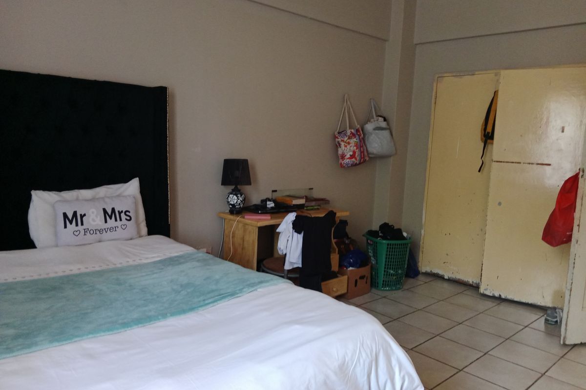A bedroom featuring tiled flooring and built-in wardrobe storage. The space offers a functional layout with neutral wall tones.
