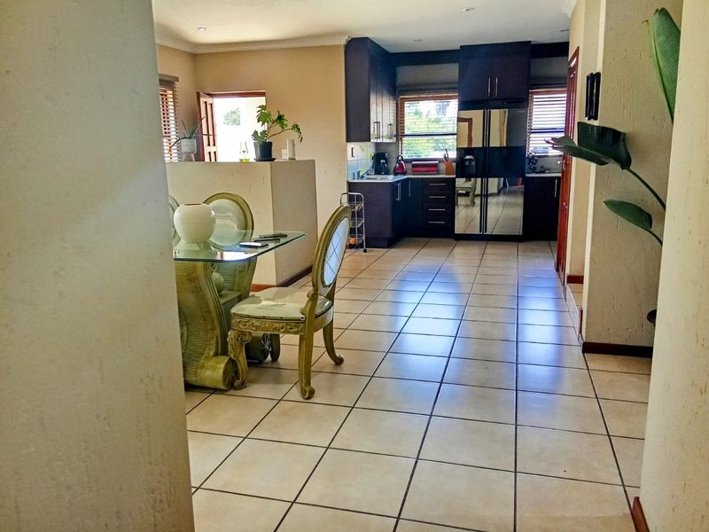 Open-plan living and kitchen area featuring tiled flooring, dark wood cabinetry, and recessed lighting, creating a functional and connected space.