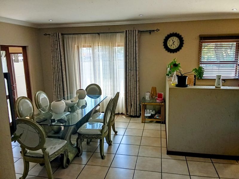 A dining area featuring tiled flooring, recessed lighting, and a half-height partition wall, with access to the outdoors via a sliding glass door.