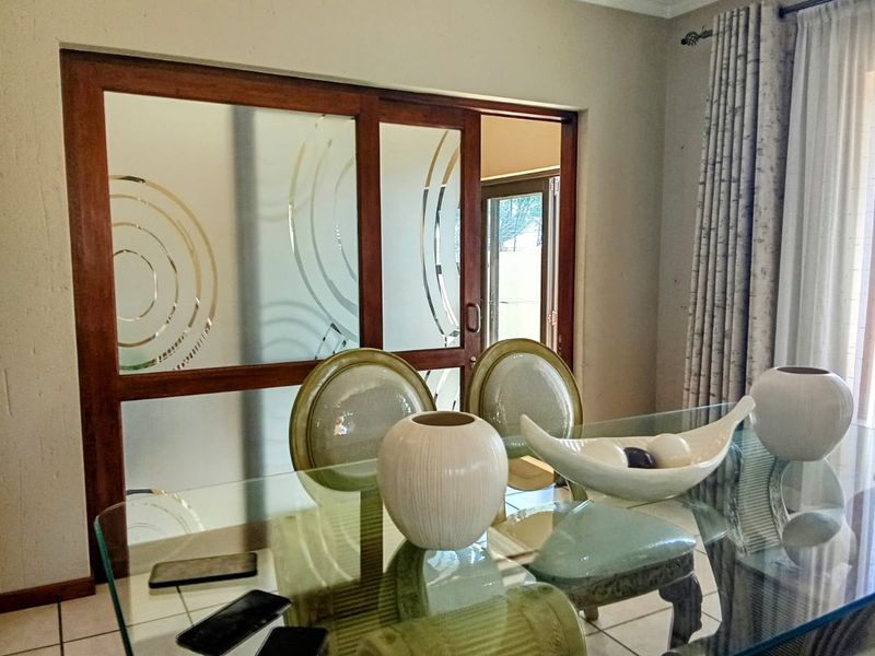 A dining area featuring tiled flooring and a decorative wooden-framed sliding glass door leading to an adjacent space.
