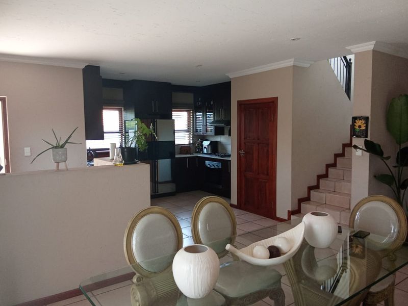 Open plan living and dining area featuring a functional kitchen with built-in cabinetry, gas hob, and oven, adjacent to a staircase.