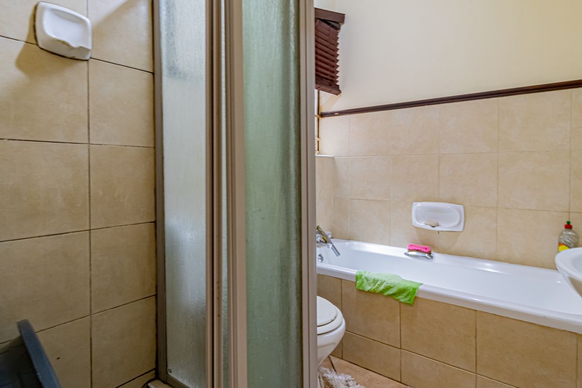 A functional bathroom featuring a built-in bathtub, a separate shower enclosure, and wall-mounted soap dishes with neutral ceramic tiling.
