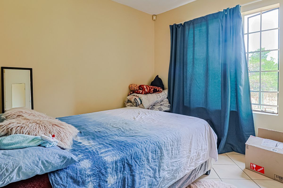 A bedroom featuring tiled flooring and a window with natural light, providing a functional space for rest.