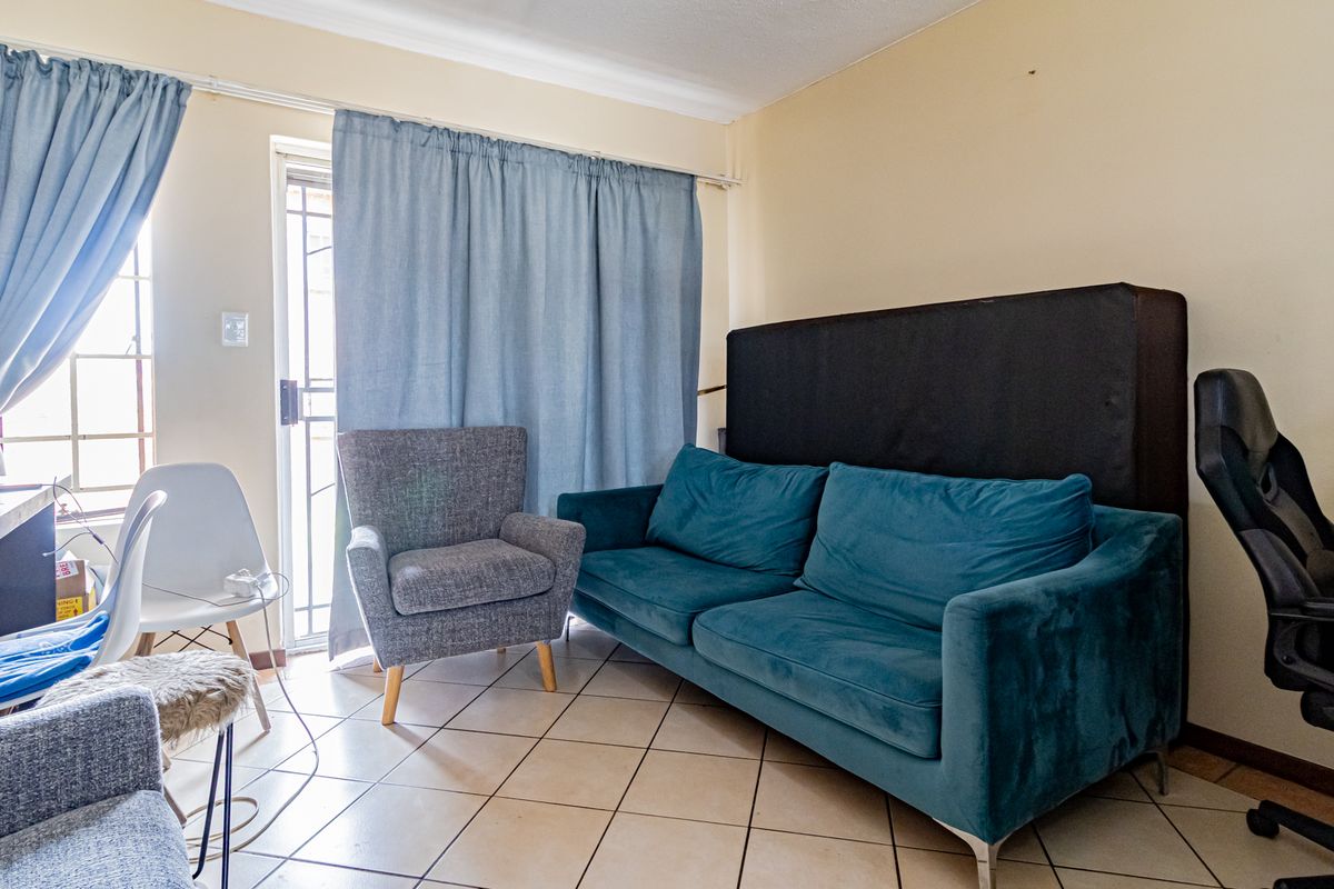 A living room area featuring tiled flooring and a sliding glass door providing access to an outdoor space.