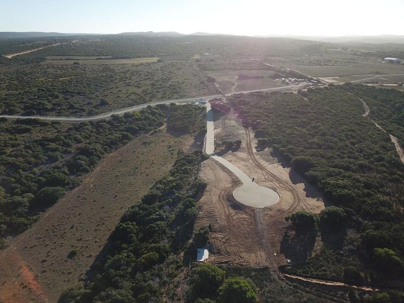 Aerial view of a rural property plot featuring a newly paved driveway and cul-de-sac turnaround area set within a natural landscape.