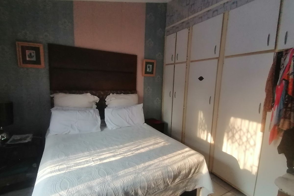 A bedroom featuring built-in cupboards and tiled flooring, offering a functional space with potential for cosmetic updates.