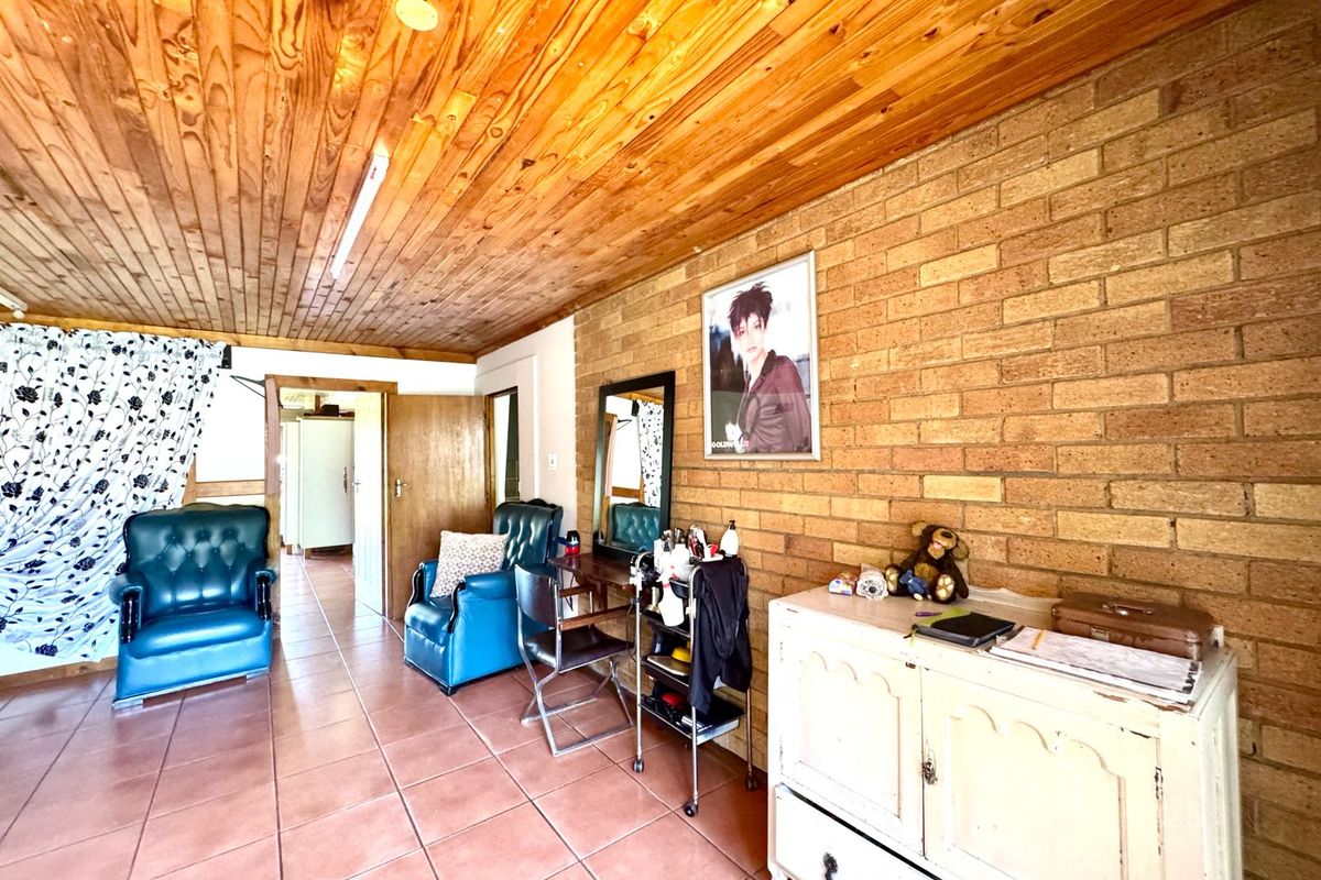 Living area featuring exposed brick walls, timber tongue and groove ceiling, and ceramic floor tiles, offering a rustic aesthetic with potential for modernization.