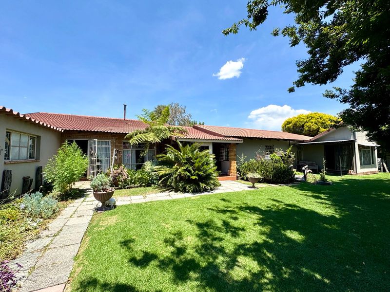A view of the rear exterior of the house featuring a well-maintained lawn, paved pathway, and traditional tiled roof.