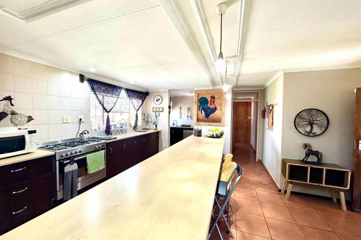 Spacious kitchen featuring dark cabinetry, a large breakfast bar, gas stove, and tiled flooring, offering a functional layout with direct access to the hallway.