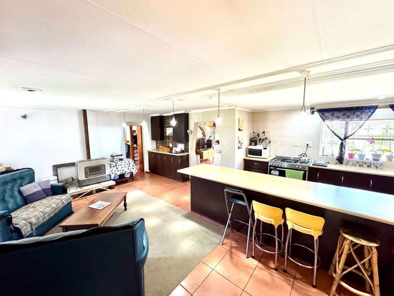 Open-plan living and kitchen area featuring a central island, dark cabinetry, gas stove, and tiled flooring throughout.
