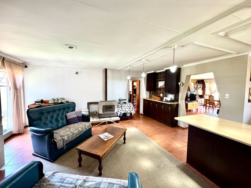 Spacious open-plan living area featuring tiled floors, a built-in fireplace, and a functional kitchen with dark cabinetry and counter space.