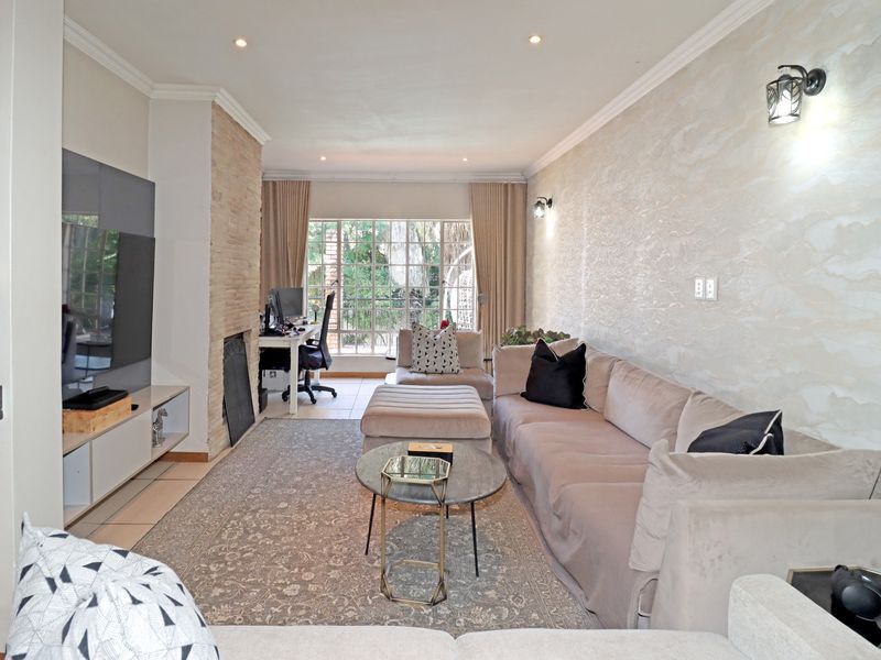 A well-maintained living room featuring a stone-clad fireplace, textured feature wall, recessed lighting, and large windows providing natural light.
