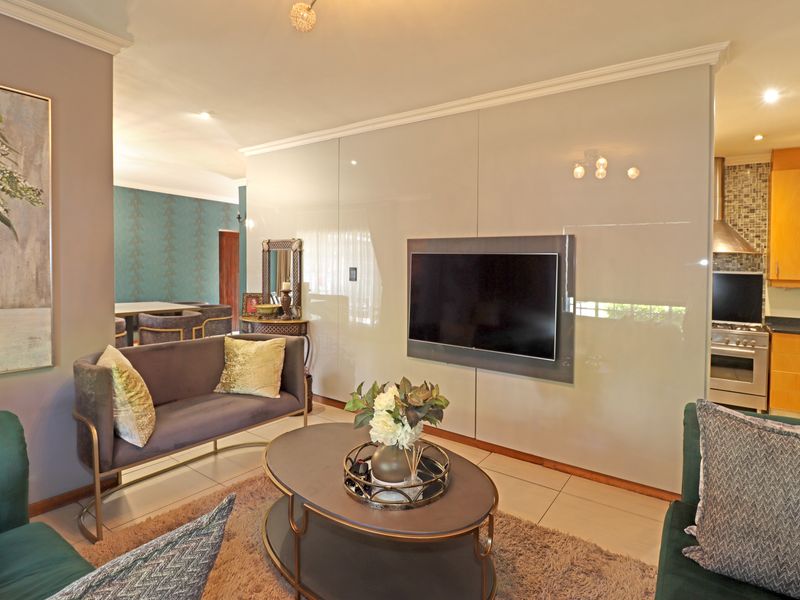 Open-plan living area featuring glossy wall paneling, tiled floors, and a modern kitchen with built-in cabinetry and stainless steel appliances.