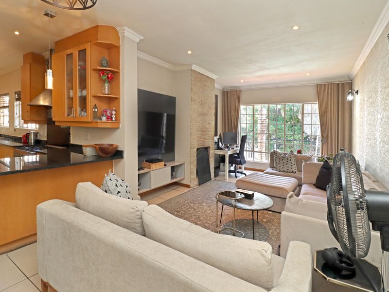 Open-plan living area featuring a modern kitchen with granite countertops, a stone fireplace, and tiled flooring, creating a functional and connected living space.