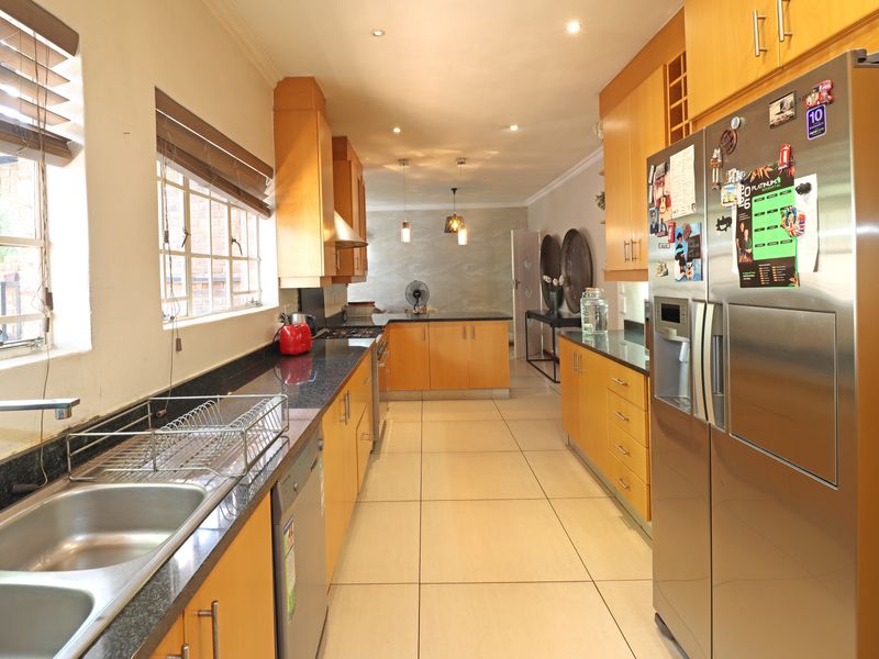A functional galley-style kitchen featuring wooden cabinetry, granite countertops, tiled flooring, and recessed lighting, offering a practical layout for daily meal preparation.