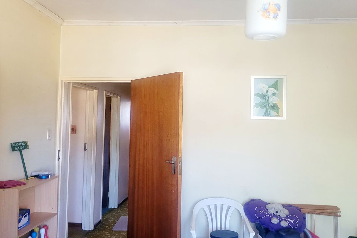 A bedroom interior featuring a built-in cupboard and access to a hallway, showing standard finishes and neutral wall tones.