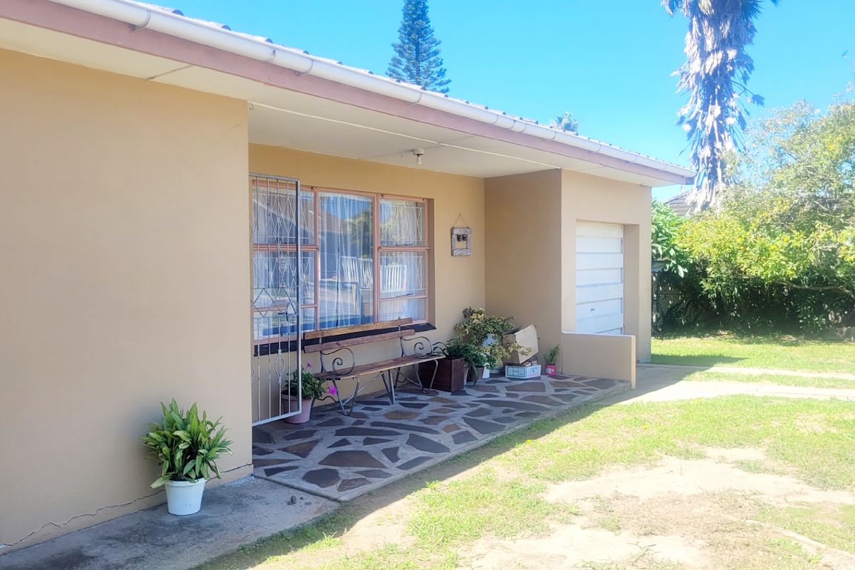 A rear view of the house featuring a covered patio with crazy paving, a security gate, and access to the garage.