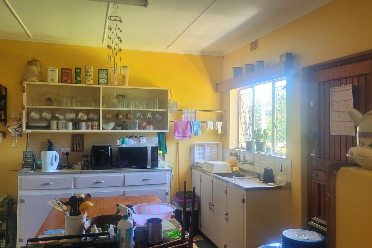 A functional kitchen featuring built-in cabinetry, a double sink, and a window with security bars, offering a traditional layout with potential for modernization.