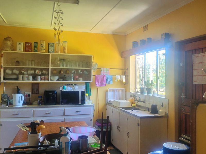 A functional kitchen featuring built-in cabinetry, a double sink, and a window with security bars, offering a traditional layout with potential for modernization.