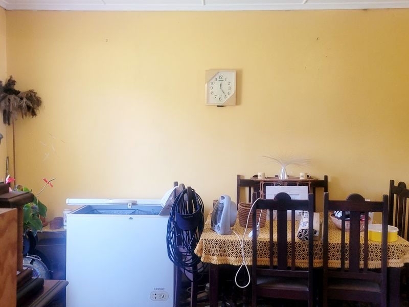 A dining room space featuring yellow painted walls and a window with a wooden pelmet.