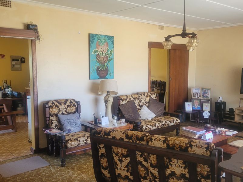 Spacious living room featuring sliding wooden doors and carpet flooring, offering a functional layout with potential for modern updates.