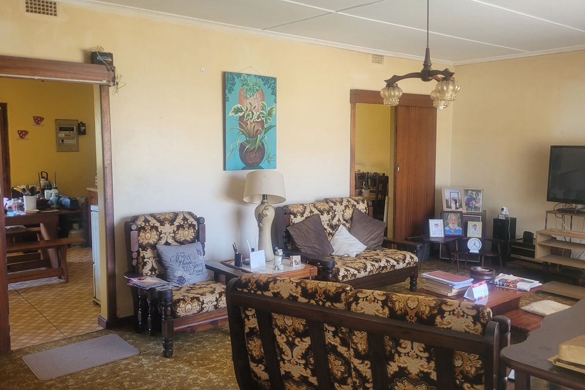 Spacious living room featuring sliding wooden doors and carpet flooring, offering a functional layout with potential for modern updates.