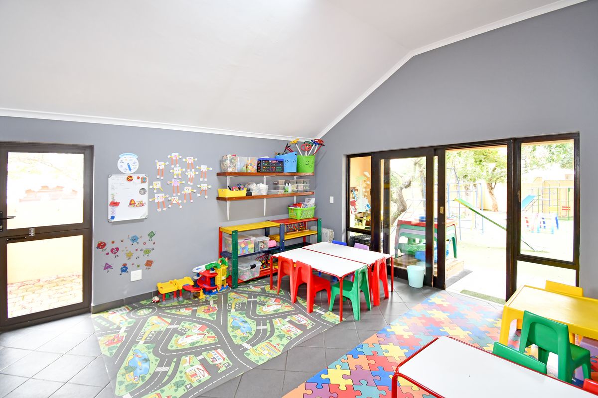 Spacious room with vaulted ceilings, tiled flooring, and large sliding glass doors providing direct access to the outdoor garden area.