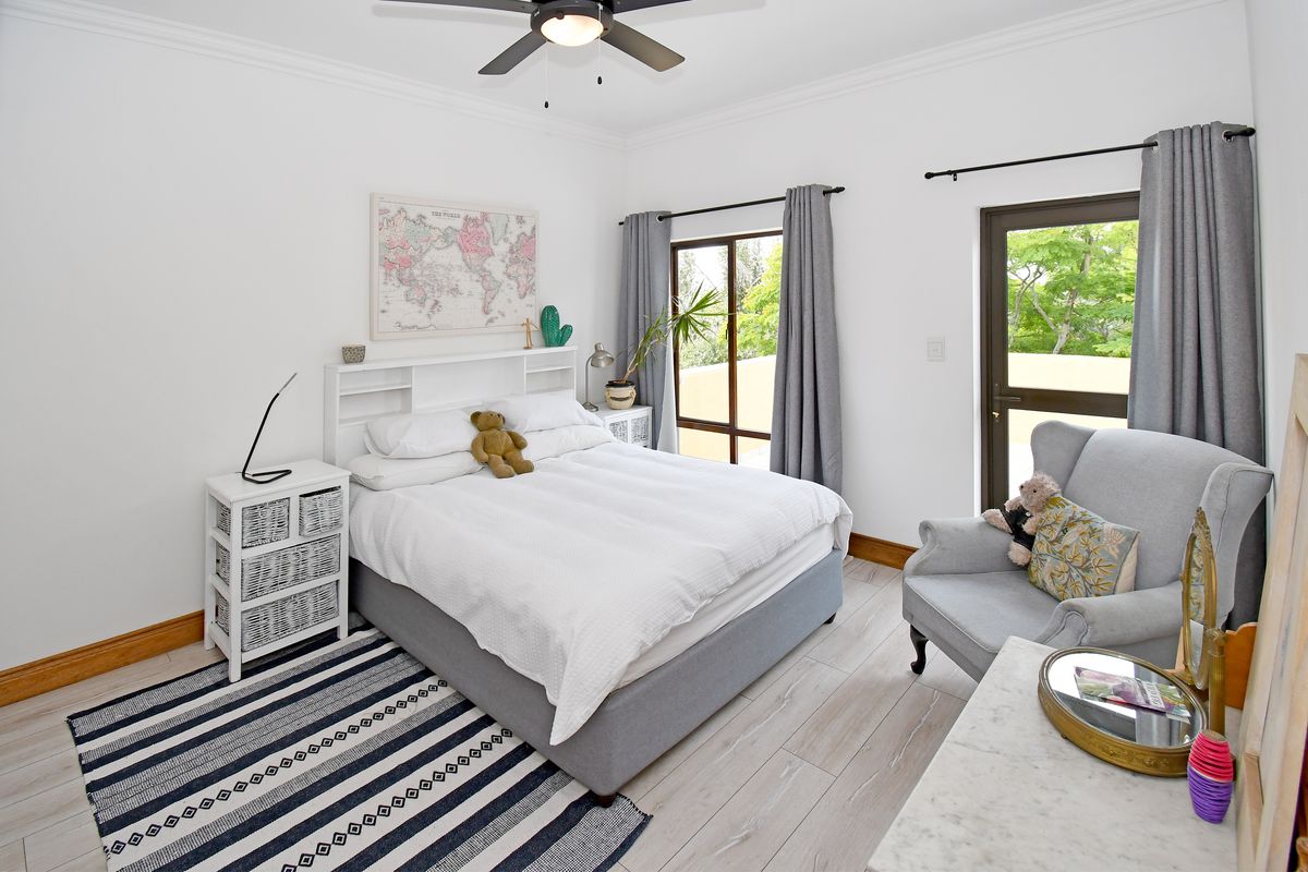 A bright bedroom featuring light wood-look flooring, crown molding, a ceiling fan, and direct access to an outdoor area through a glass door.